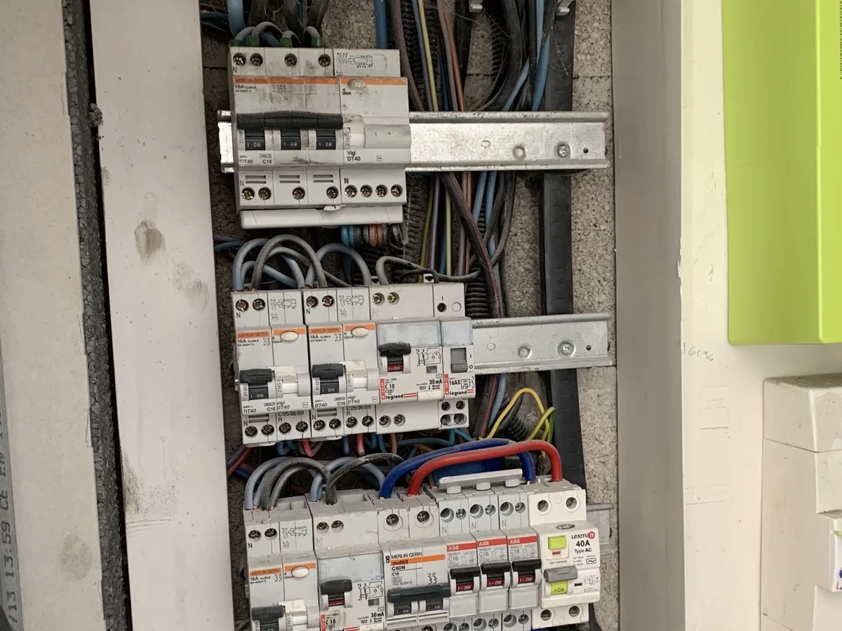 Tableau électrique ouvert avec rangées de disjoncteurs, interrupteurs différentiels et peignes de raccordement